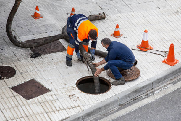 deux travailleurs dans la rue de la ville débloquent un égout avec un tuyau d’arrosage - tuyau darrosage photos et images de collection