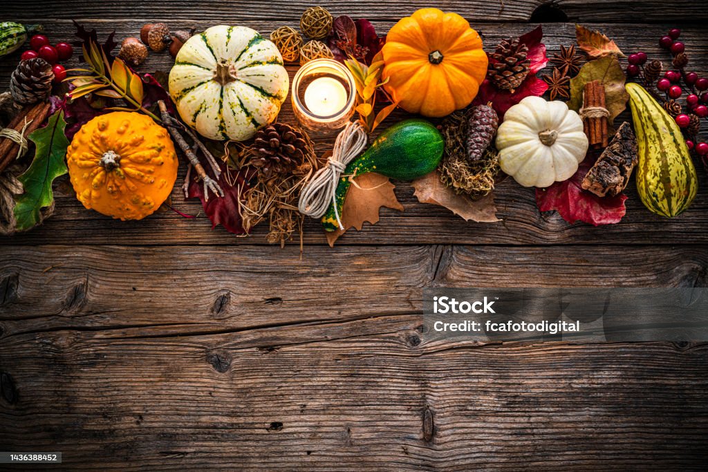 Autumn or Thanksgiving decoration border with mini pumpkins and dry leaves. Copy space Autumn or Thanksgiving decoration: overhead view of gourds, dry leaves, burning candle, pine cones shot on rustic wooden table. The composition is at the top of an horizontal frame leaving useful copy space for text and/or logo. High resolution 42Mp studio digital capture taken with SONY A7rII and Zeiss Batis 40mm F2.0 CF lens Thanksgiving - Holiday Stock Photo