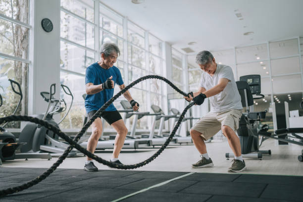 Asian Chinese Senior personal trainer encouraging senior man practicing battle rope in gym Asian Chinese Senior personal trainer encouraging senior man practicing battle rope in gym exercise stock pictures, royalty-free photos & images