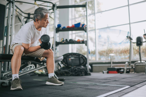 entrenamiento asiático chino senior man con mancuernas en el gimnasio - body care asian ethnicity body building toughness fotografías e imágenes de stock