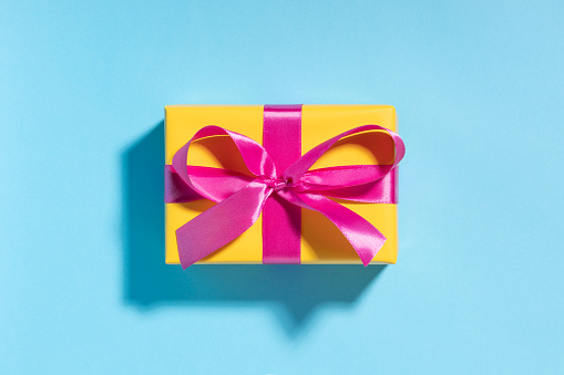 Pink gift box with yellow ribbon on blue. This file is cleaned and retouched.