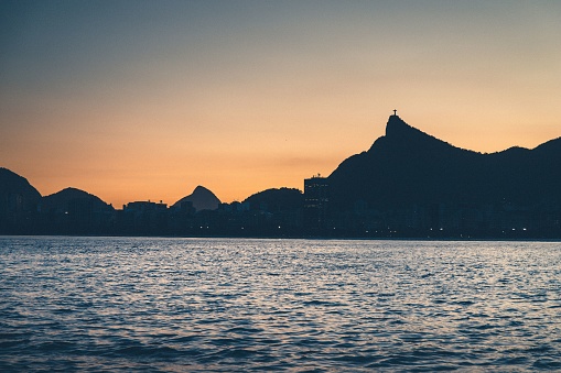 A silhouette of cityscape Rio de Janeiro surrounded by buildings and water during sunset
