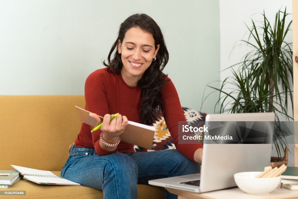 Happy girl freelancing at her living room Portrait of a young woman working online from her living room 25-29 Years Stock Photo