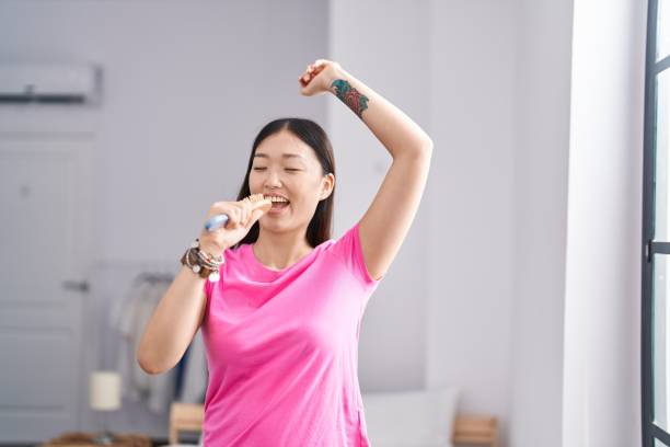 istock Chinese woman singing song using brush as a microphone at bedroom 1436393757