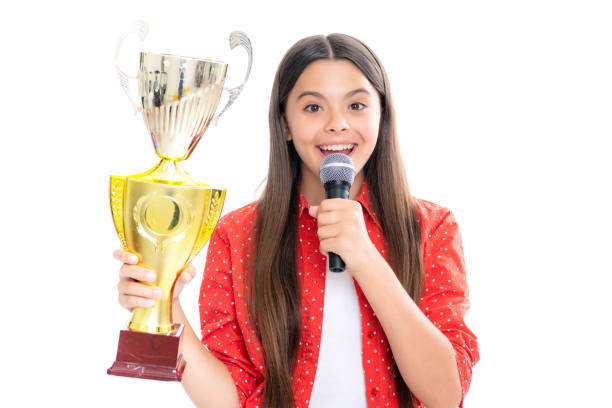 fille avec un discours de microphone de coupe gagnante. adolescent tenant un trophée. l’enfant gagnant a remporté la compétition, célébrant le succès et la victoire. portrait d’une adolescente heureuse et souriante. - elementary age focus on foreground indoors studio shot photos et images de collection