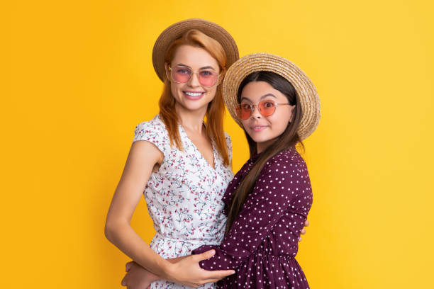 улыбающиеся мать и ребенок в соломенной шляпе на желтом фоне - fun mother sunglasses family стоковые фото и изображения