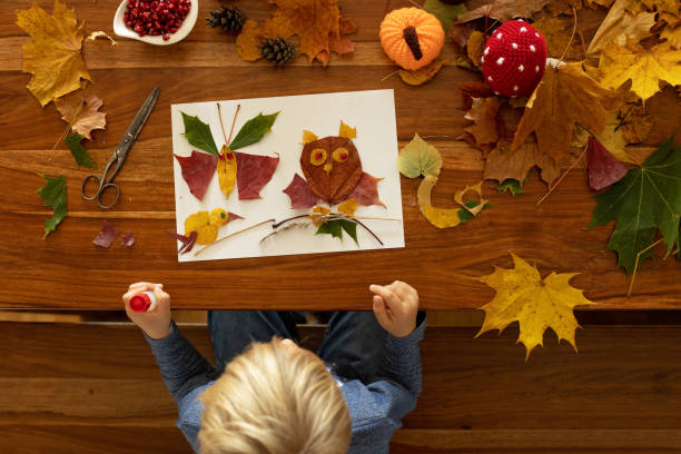 istock Child, applying leaves using glue, scissors, and paint, while doing arts and crafts at home 1436396568