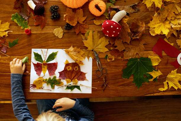 istock Child, applying leaves using glue, scissors, and paint, while doing arts and crafts at home 1436396877