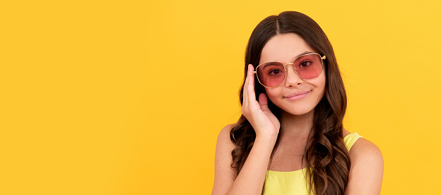 happy child in summer glasses has curly hair on yellow background, beauty. Child face, horizontal poster, teenager girl isolated portrait, banner with copy space