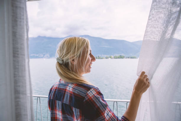 istock Woman opening curtains in room 1436400726