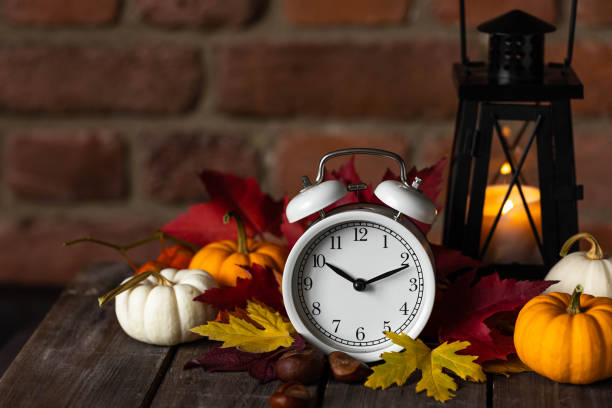 istock Fall winter time change concept. Autumn composition with retro alarm clock, bright yellow and red leaves, walnut. Brick wall on background. Cozy home atmosphere. Close-up 1436402506
