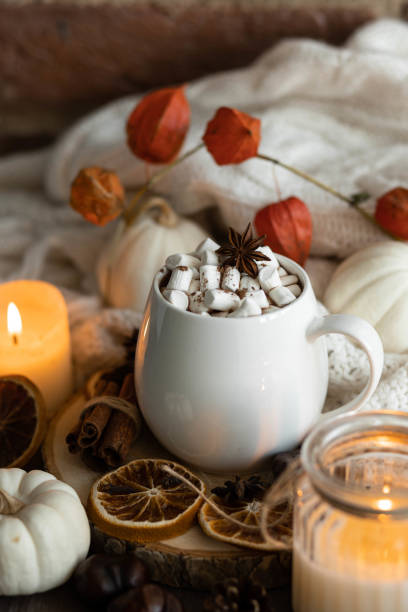 istock Autumn cozy home composition with hot chocolate with marshmallow and candles. Aromatherapy on a grey fall morning, atmosphere of cosiness and relax. Wooden background, window sill, close up. 1436402654