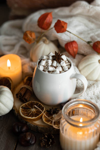 istock Autumn cozy home composition with hot chocolate with marshmallow and candles. Aromatherapy on a grey fall morning, atmosphere of cosiness and relax. Wooden background, window sill, close up. 1436402661
