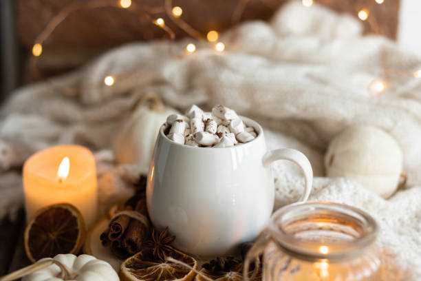 istock Autumn cozy home composition with hot chocolate with marshmallow and candles. Aromatherapy on a grey fall morning, atmosphere of cosiness and relax. Wooden background, window sill, close up. 1436402689