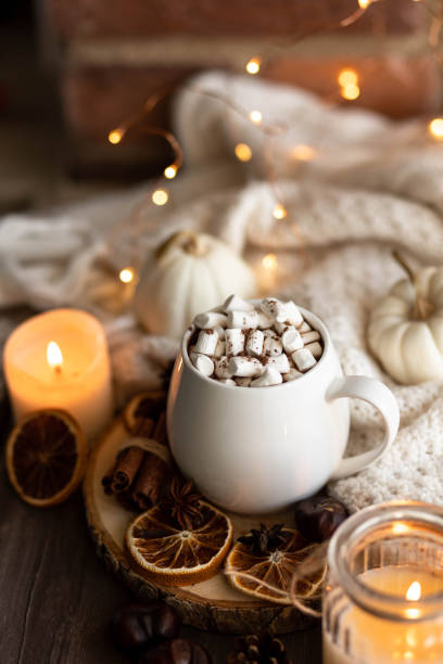 istock Autumn cozy home composition with hot chocolate with marshmallow and candles. Aromatherapy on a grey fall morning, atmosphere of cosiness and relax. Wooden background, window sill, close up. 1436402717
