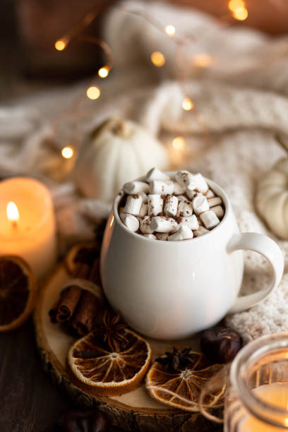 istock Autumn cozy home composition with hot chocolate with marshmallow and candles. Aromatherapy on a grey fall morning, atmosphere of cosiness and relax. Wooden background, window sill, close up. 1436402729