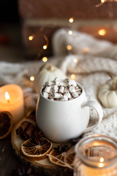 istock Autumn cozy home composition with hot chocolate with marshmallow and candles. Aromatherapy on a grey fall morning, atmosphere of cosiness and relax. Wooden background, window sill, close up. 1436402732
