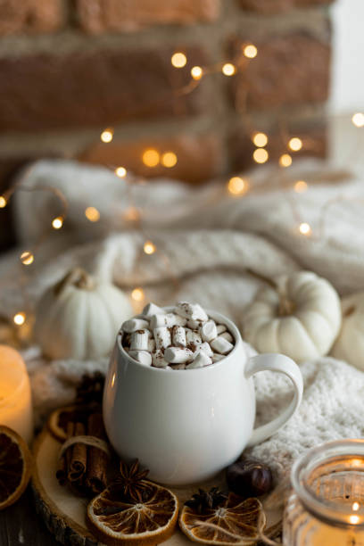 istock Autumn cozy home composition with hot chocolate with marshmallow and candles. Aromatherapy on a grey fall morning, atmosphere of cosiness and relax. Wooden background, window sill, close up. 1436402735