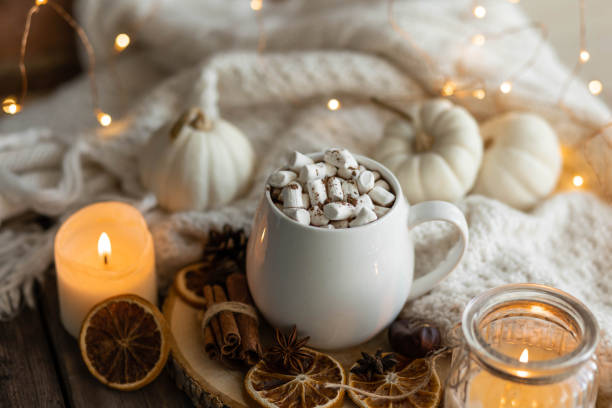istock Autumn cozy home composition with hot chocolate with marshmallow and candles. Aromatherapy on a grey fall morning, atmosphere of cosiness and relax. Wooden background, window sill, close up. 1436402759
