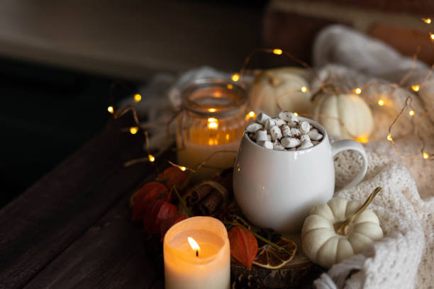 istock Autumn cozy home composition with hot chocolate with marshmallow and candles. Aromatherapy on a grey fall morning, atmosphere of cosiness and relax. Wooden background, window sill, close up. 1436402836