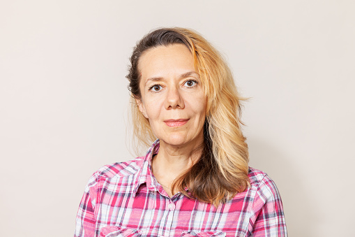 Close-up studio portrait of a 45 year old white woman in a plaid shirt on a white background