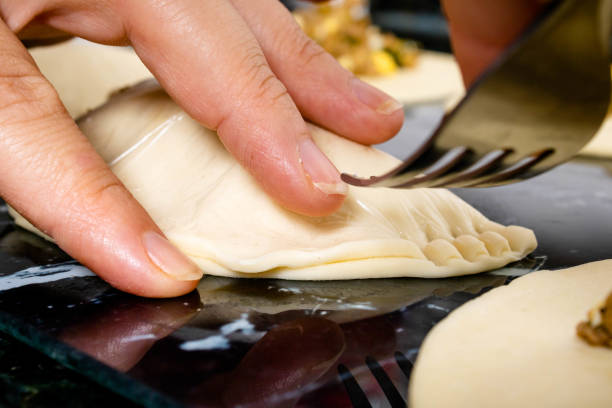 istock Pastry preparation with puff pastry being closed with a fork on the edges before baking. Mention food preparation in the kitchen at home, fast and practical food. 1436405946