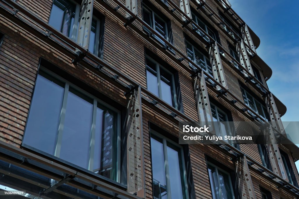 Exterior of modern red brick house with metal inserts. Architectural detail of close-up on windows. Real estate, residential apartments and offices. Living apartments or office building architecture. Advertisement Stock Photo