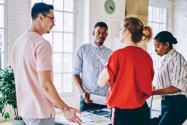 istock Multiracial crew of young hipsters have briefing meeting for collaborate on workshop project, intelligent millennials discussing organisation planning talking near table desk with documents 1436408437