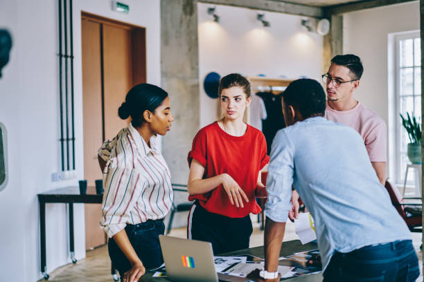 istock Group of diverse hipster students team working on development of startup ideas collaborating near table desk with modern netbook and paper documents, intelligent professionals research briefing info 1436408487