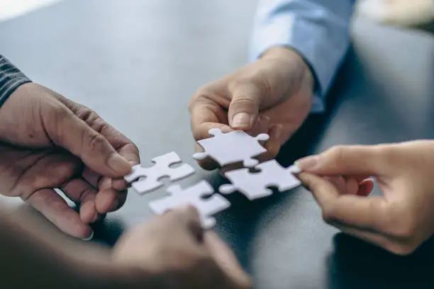 Photo of People holds in hand a jigsaw puzzle. Business solutions, success and strategy.Group of business people assembling jigsaw puzzle