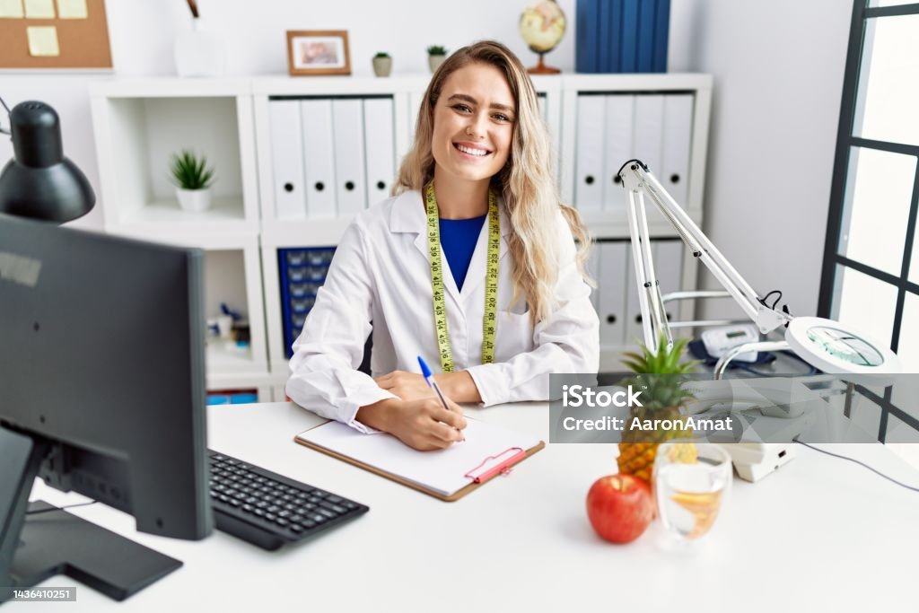 Young woman dietician writing on document at clinic Nutritionist Stock Photo