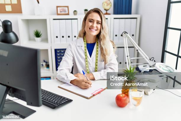 Young Woman Dietician Writing On Document At Clinic Stock Photo - Download Image Now