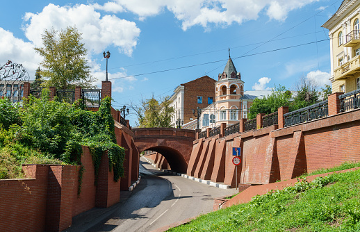 Picturesque red stone bridge overhangs across the road. Bridge was  designed by Voronezh architect Ivan Blitsyn in 1826. Voronezh, Russia - July 30, 2022