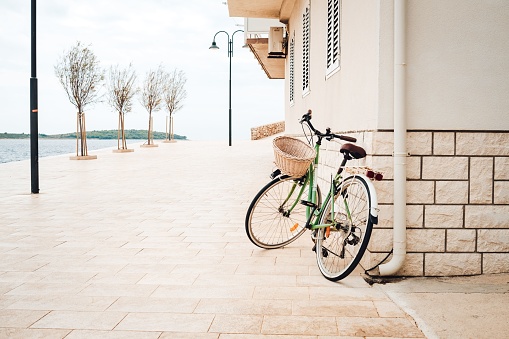 A green bicycle with a basket leaning on a stone wall in a coastal town in Croatia