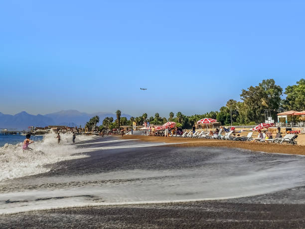 Antalya, Turkey - October 26, 2019: People relax on Lara Beach in Antalya. High tide and big waves on the Mediterranean Sea against the background of umbrellas and sun loungers on the sandy shore