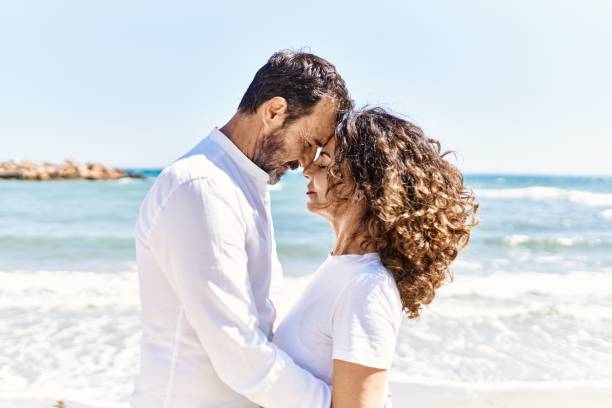 istock Middle age hispanic couple hugging at the beach. 1436414665