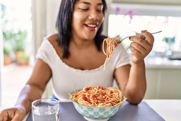 istock Hispanic brunette woman eating spaghetti at the kitchen 1436415220