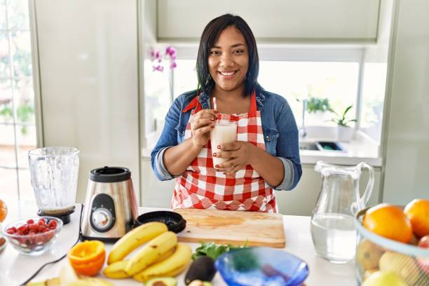 istock Hispanic brunette woman drinking fresh fruit smoothie at the kitchen 1436415288