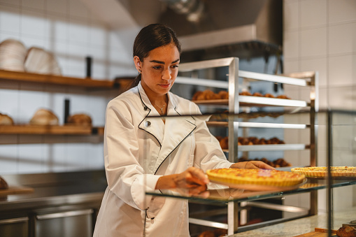 Young Hispanic Baker Arranging The Pastry For Sale