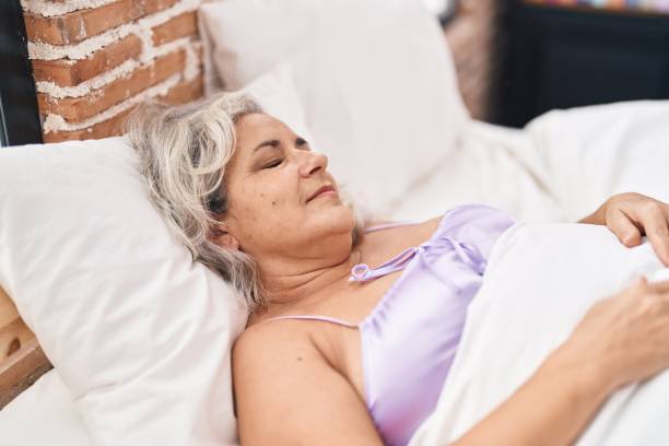 istock Middle age grey-haired woman lying on bed sleeping at bedroom 1436415616