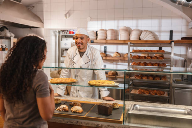 istock Hispanic Chef Serving Delicious Bread In His Bakery Shop 1436415926