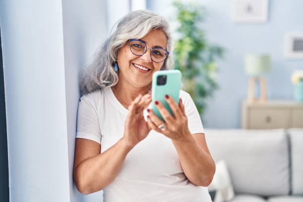 istock Middle age woman using smartphone standing at home 1436415978