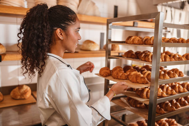 istock Female Baker Arranging Freshly Baked Croissants 1436416445