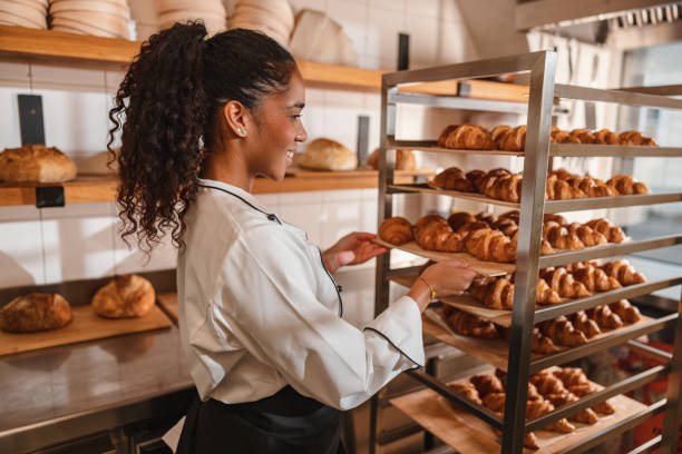 istock Female Baker Arranging Freshly Baked Croissants 1436416449