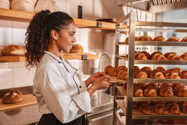 istock Female Baker Arranging Freshly Baked Croissants 1436416629
