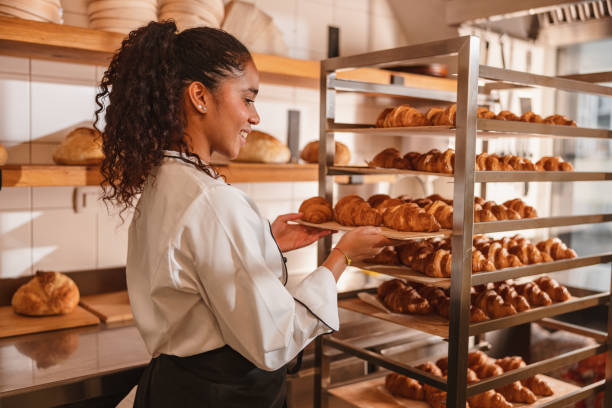 istock Female Baker Arranging Freshly Baked Croissants 1436416633