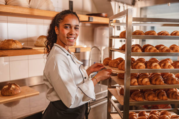 istock Female Baker Arranging Freshly Baked Croissants 1436416635