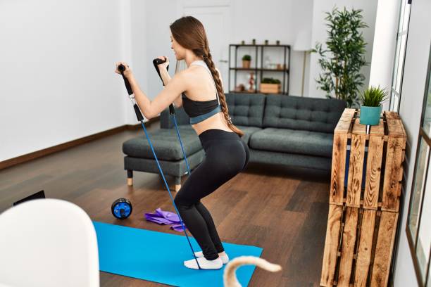 istock Young hispanic woman smiling confident having online traininig using elastic band at home 1436418297