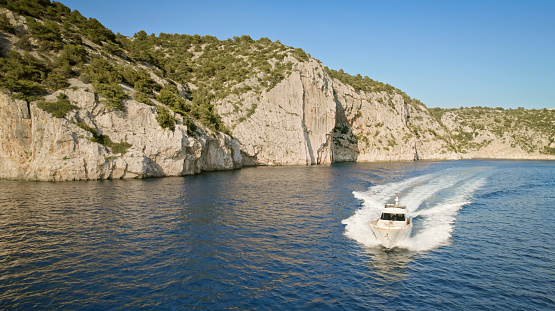 Aerial view of luxury yacht cruising in sea against coastline.