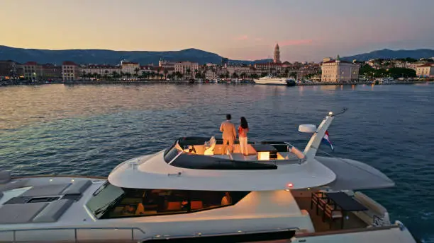 Couple standing on luxury yacht in Adriatic sea against city, Split, Croatia.